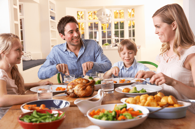 Picture of a family eating dinner together at a table.  Mom, Dad and 2 kids,